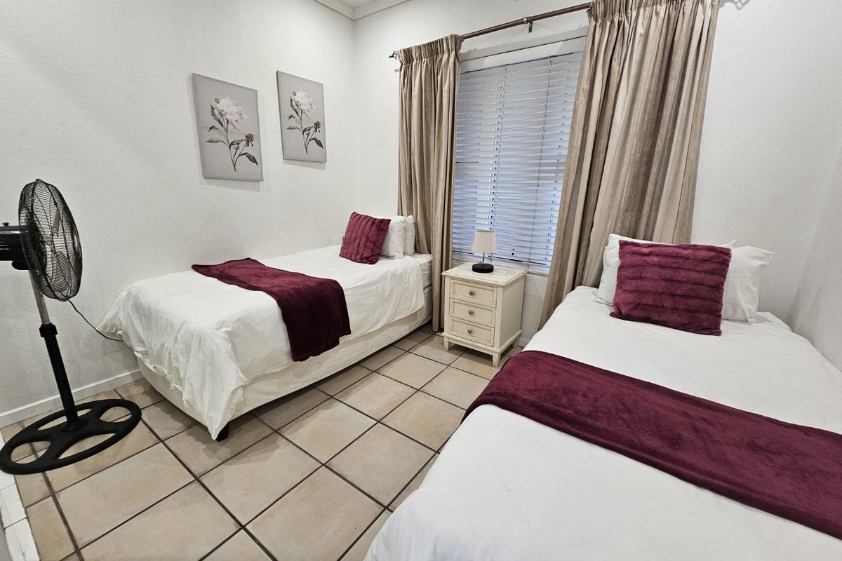 A functional bedroom featuring tiled flooring, window blinds, and curtain rails, providing a neutral base for potential interior updates.