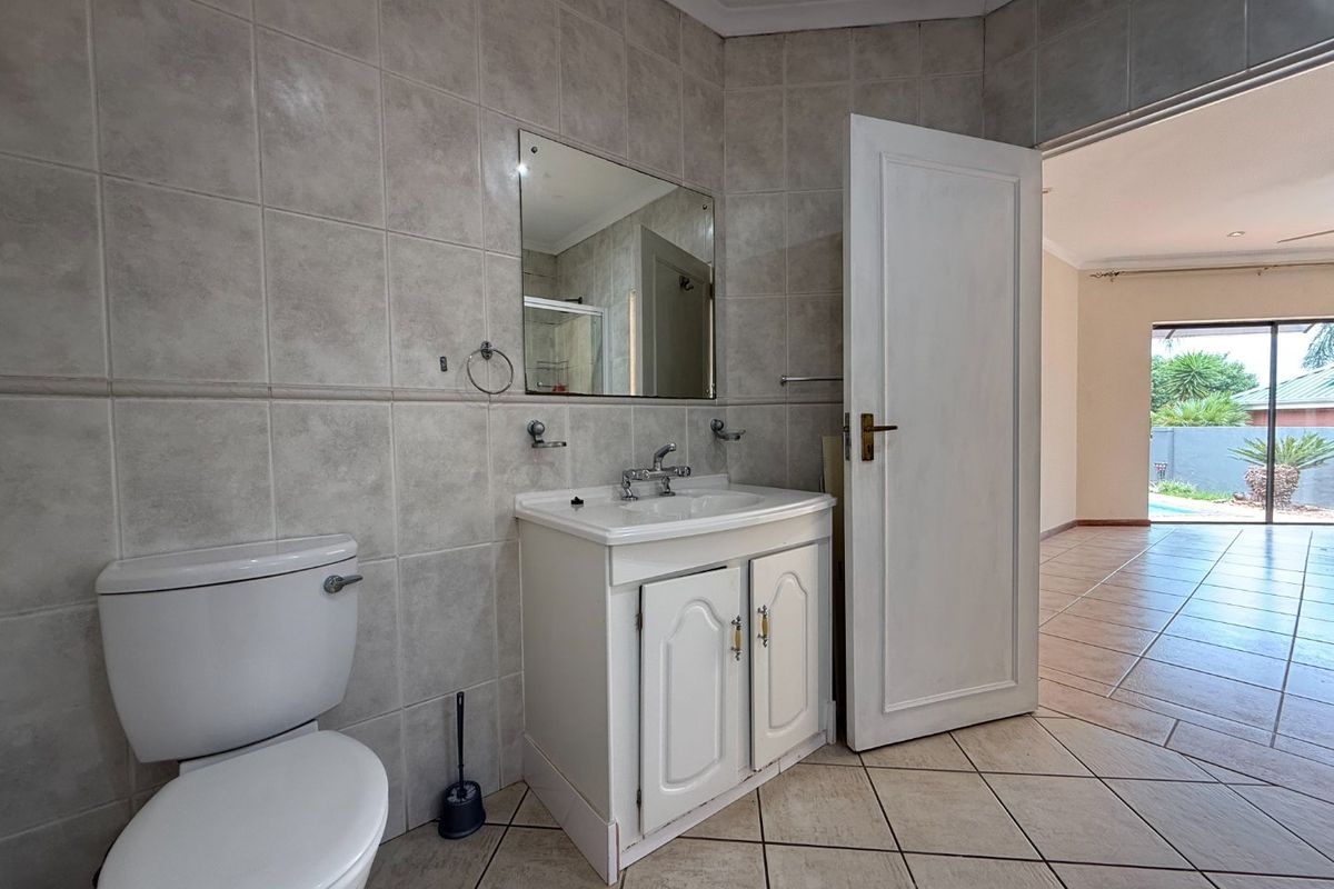 A functional bathroom featuring a vanity cabinet with a basin, wall-mounted mirror, and tiled finishes, with direct access to the adjacent living area.