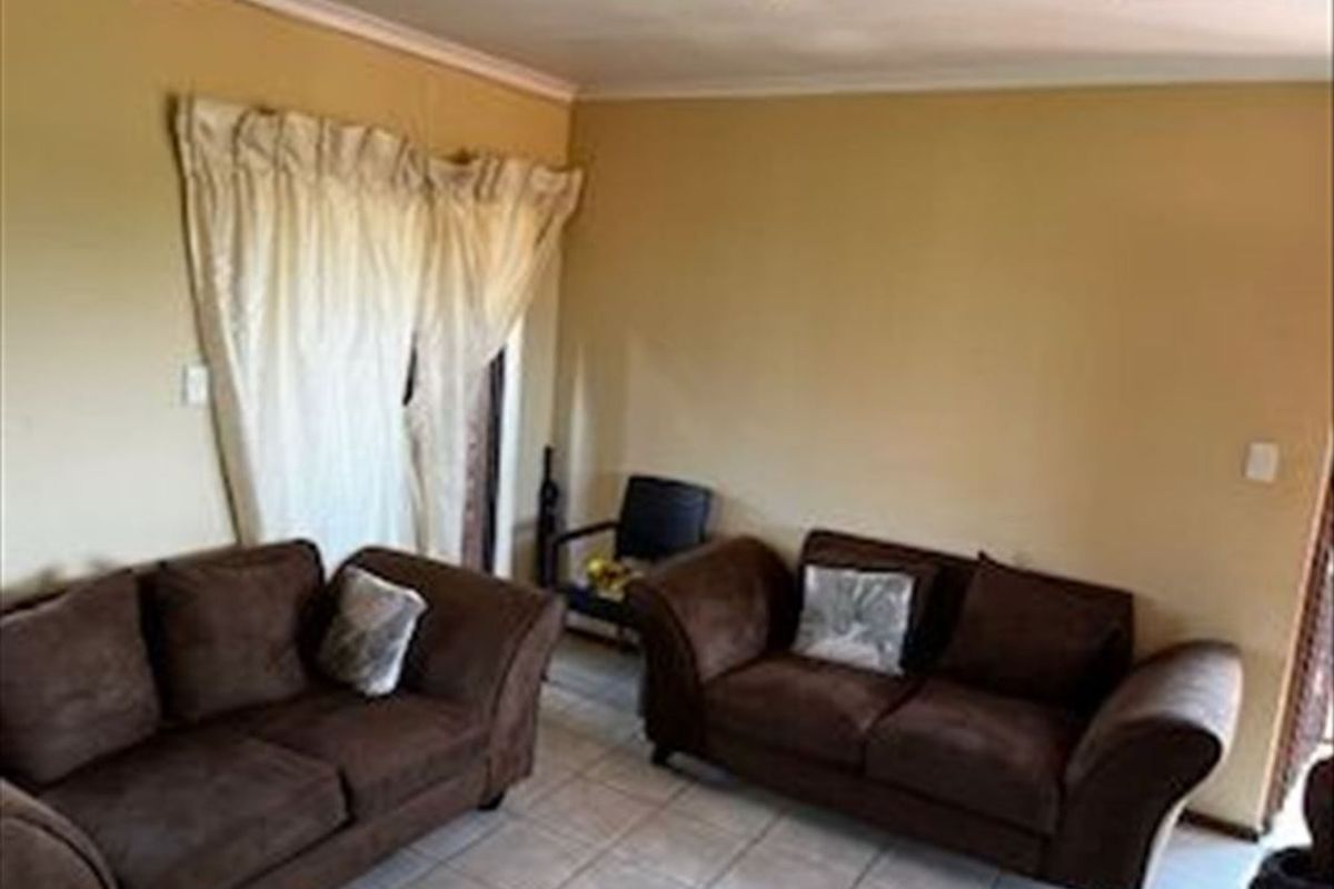 A living room area featuring tiled flooring and coved ceiling cornices, providing a functional space for relaxation.
