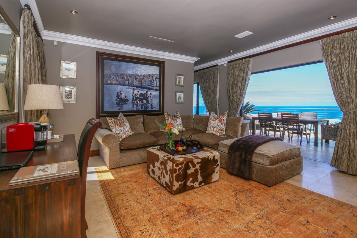 Spacious living room featuring crown molding, recessed lighting, and large sliding glass doors that open onto a balcony with ocean views.