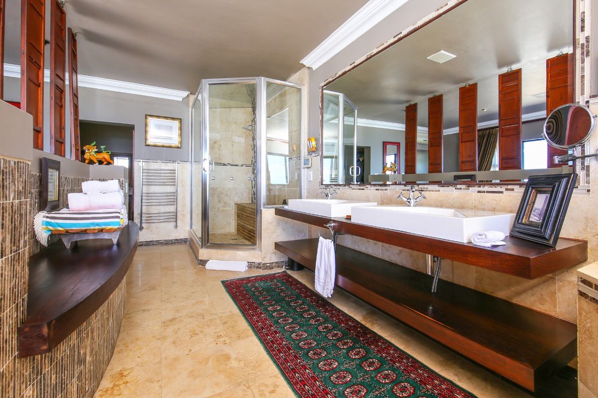 Spacious modern bathroom featuring a double vanity with vessel sinks, large wall mirror, and a separate walk-in shower with stone tiling.