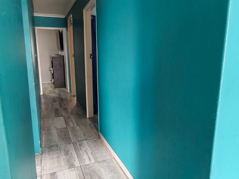A functional hallway featuring tiled flooring and painted walls, providing access to multiple rooms within the home.