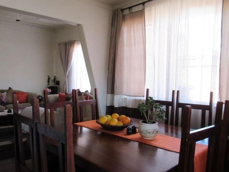 An open-plan living and dining area featuring hardwood flooring, coved cornicing, and large windows that provide ample natural light.