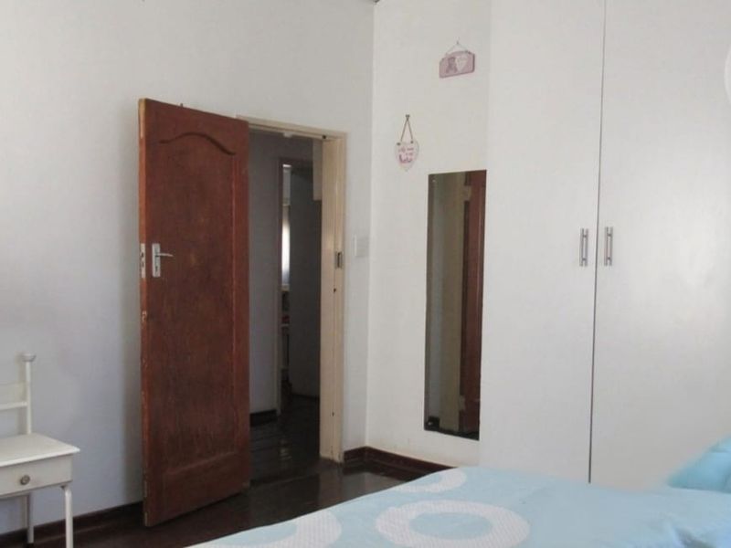 A bedroom featuring built-in cupboards and a timber door, providing functional storage and access to the hallway.