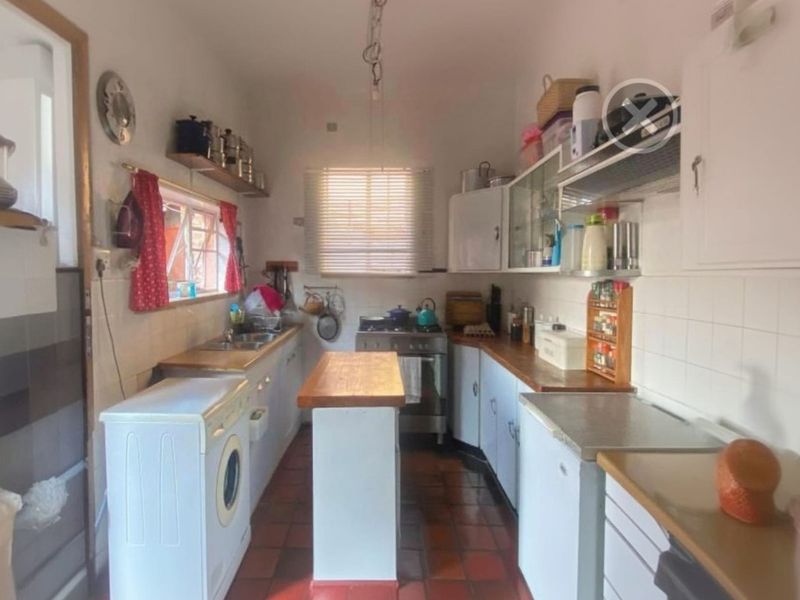 A functional kitchen featuring wooden countertops, built-in cabinetry, a stainless steel sink, and a freestanding stove with an extractor fan.