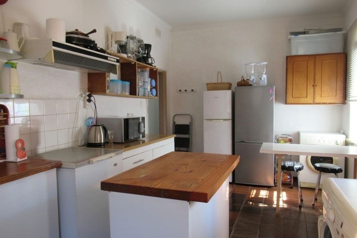 A functional kitchen featuring tiled backsplash, laminate countertops, and built-in cabinetry, offering a dated aesthetic with potential for modernization.