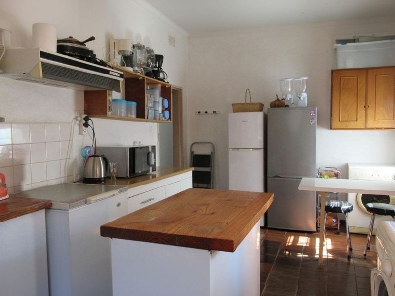 A functional kitchen featuring tiled backsplash, laminate countertops, and built-in cabinetry, offering a dated aesthetic with potential for modernization.