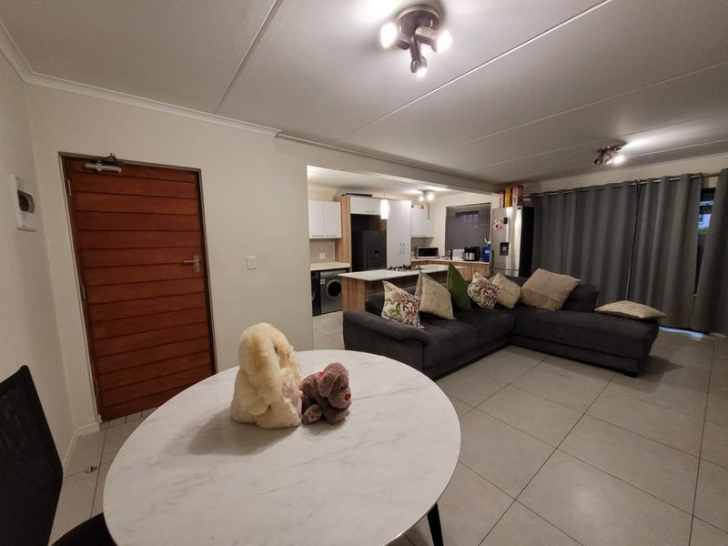 Open-plan living and kitchen area featuring tiled floors, modern cabinetry, a central kitchen island with built-in appliances, and direct access to the living space.
