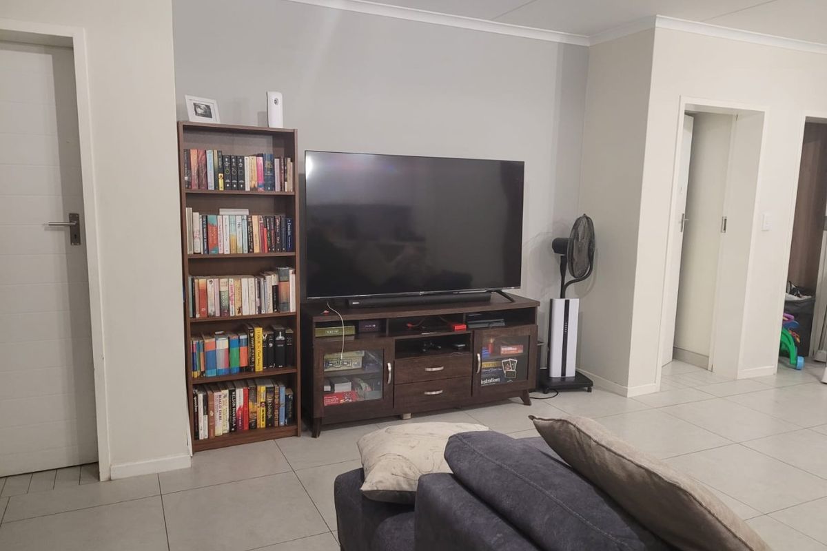 A well-maintained living room featuring neutral wall tones, tiled flooring, and clean architectural lines, providing a versatile space for relaxation.