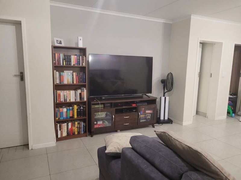 A well-maintained living room featuring neutral wall tones, tiled flooring, and clean architectural lines, providing a versatile space for relaxation.