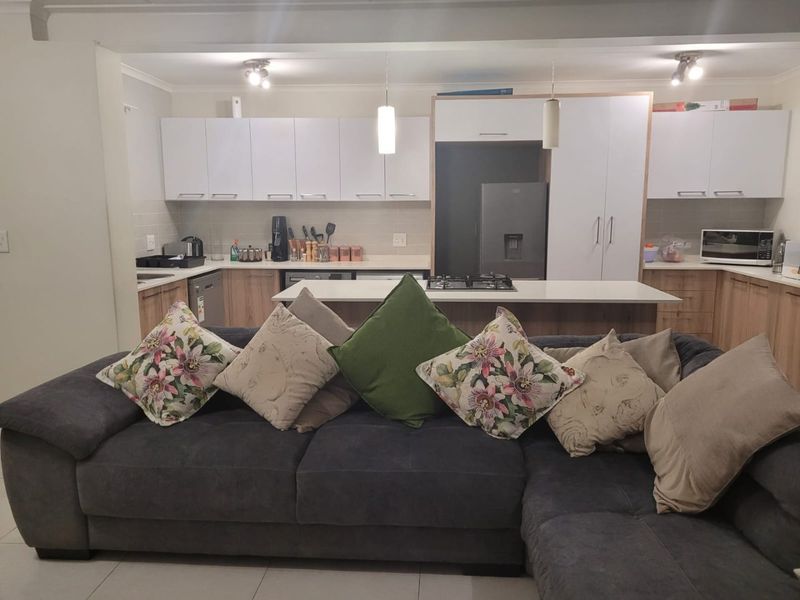 Modern open-plan kitchen featuring sleek cabinetry, a central island with a gas hob, and tiled flooring, seamlessly integrated with the living area.