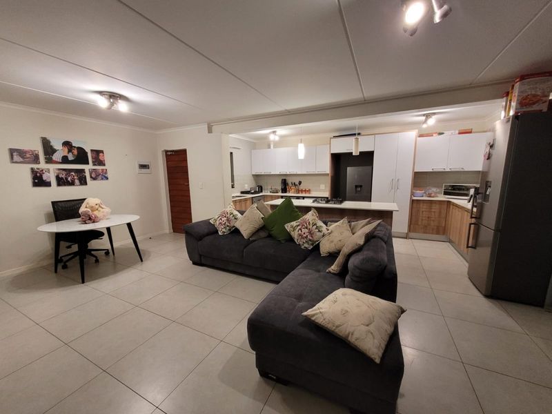 Open-plan living area featuring a modern kitchen with island, ample cabinetry, and tiled flooring, seamlessly connecting to the dining and lounge space.