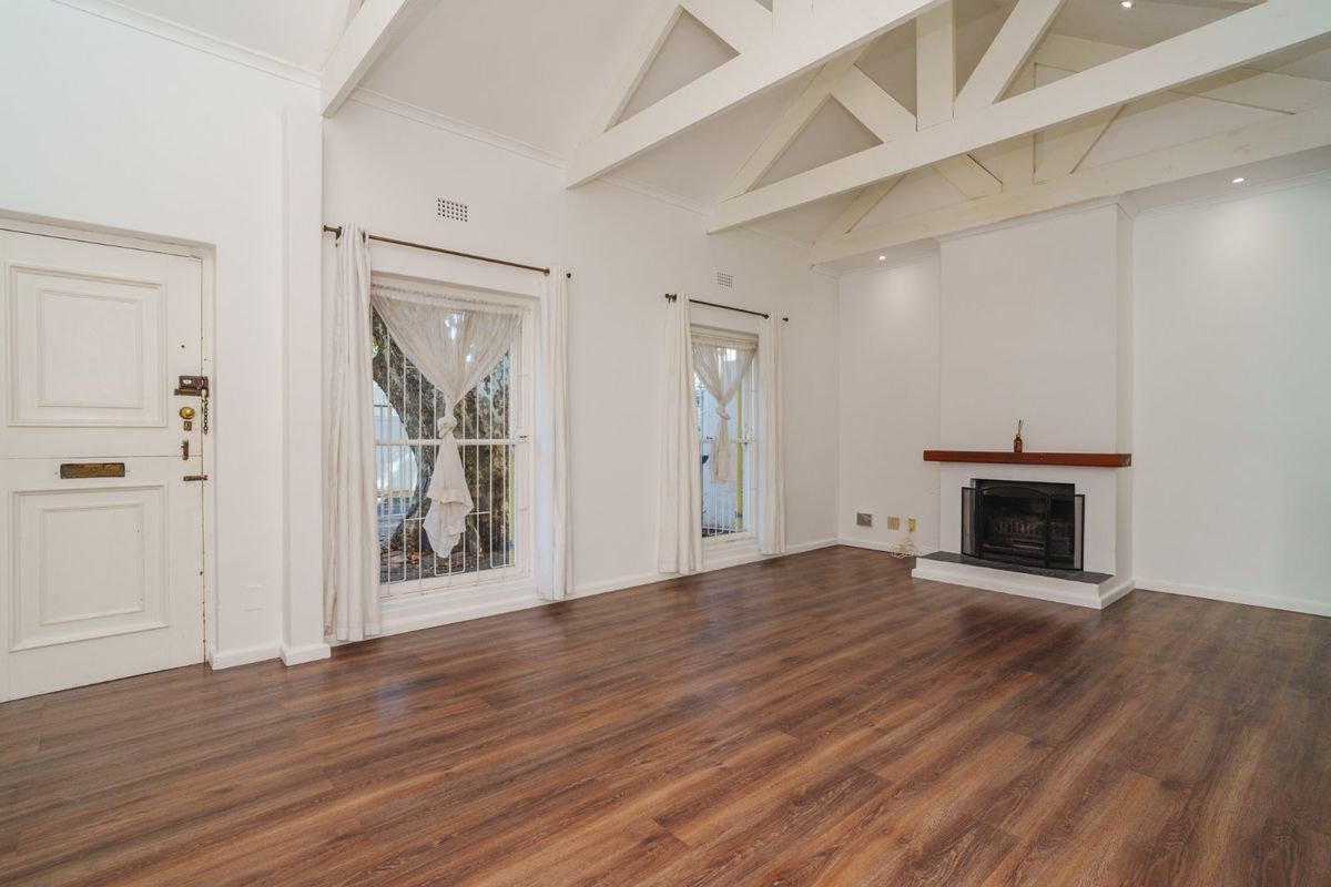 Spacious living room featuring high vaulted ceilings with exposed timber trusses, a fireplace with a timber mantelpiece, and modern laminate flooring.