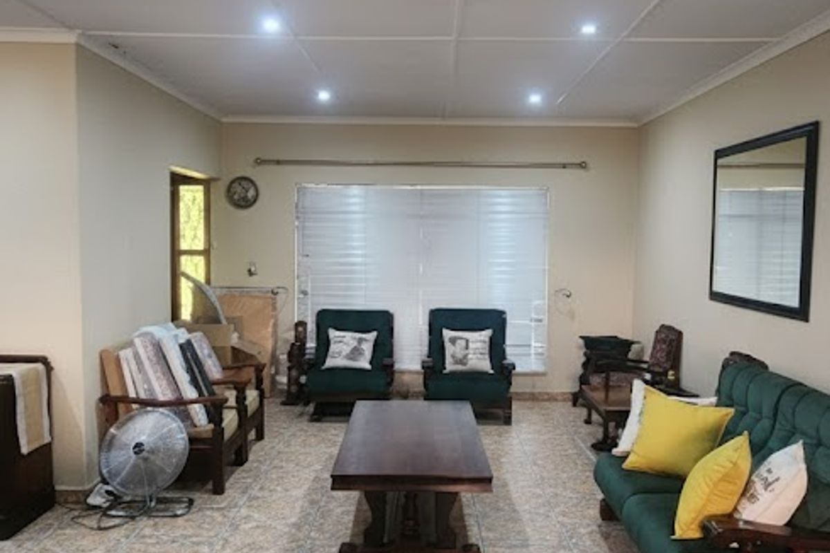 Spacious living room featuring tiled flooring, recessed downlighting, and large windows with venetian blinds, offering a comfortable and functional living space.
