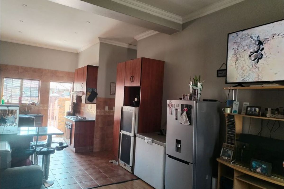 Open-plan living and kitchen area featuring tiled and laminate flooring, built-in cabinetry, and integrated kitchen appliances.
