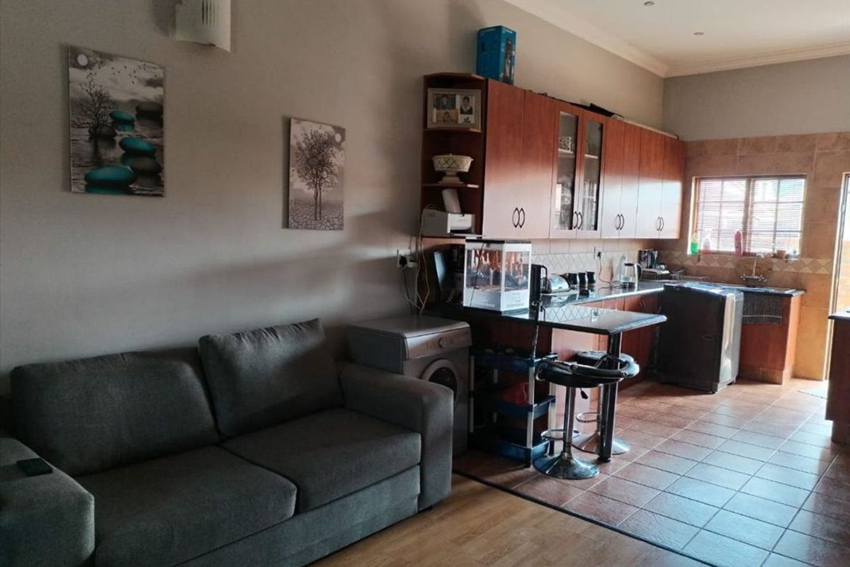 Open-plan living and kitchen area featuring a combination of tiled and laminate flooring, built-in cabinetry, and a functional kitchen layout.