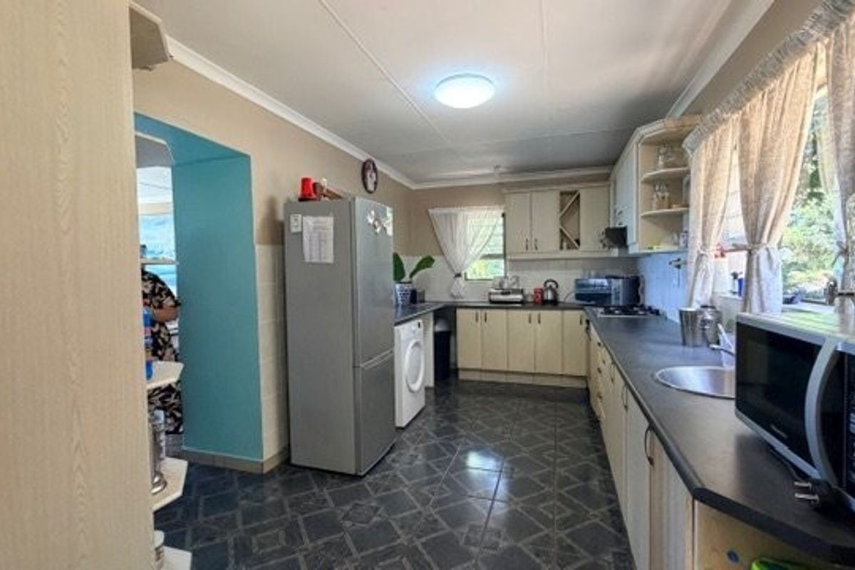 A functional kitchen featuring built-in cabinetry, laminate countertops, a stainless steel sink, and tiled flooring with a practical layout.