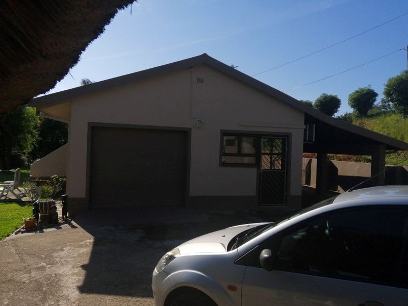 Exterior view of a residential garage featuring a roll-up door, side security gate, and an adjacent covered carport area.