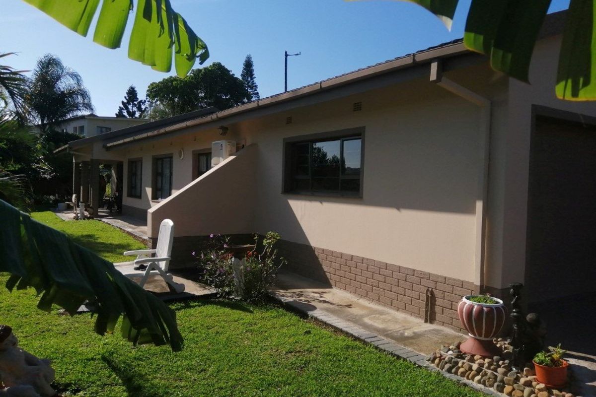 Rear view of the house featuring a paved walkway, brick base detailing, and a well-maintained lawn area.