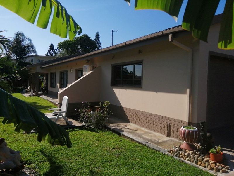 Rear view of the house featuring a paved walkway, brick base detailing, and a well-maintained lawn area.