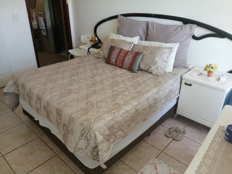 A functional bedroom featuring tiled flooring and direct access to an en-suite bathroom.