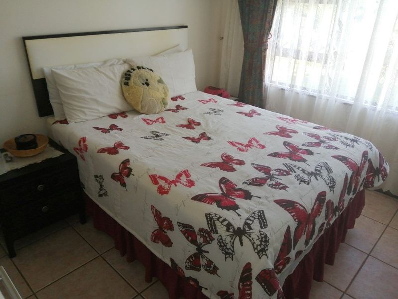 A bedroom featuring tiled flooring and a window with curtains, providing a functional space for rest.