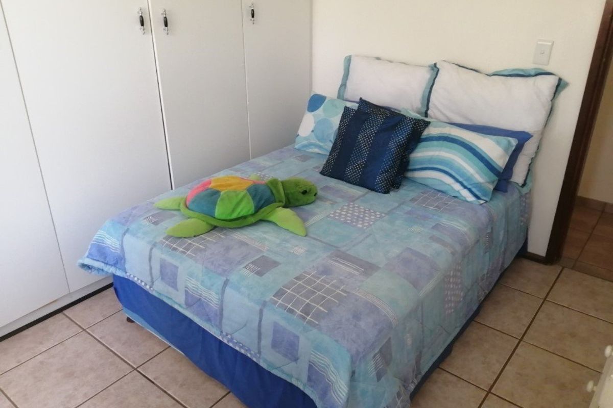 A functional bedroom featuring built-in cupboards and neutral tiled flooring, providing a clean and practical space.