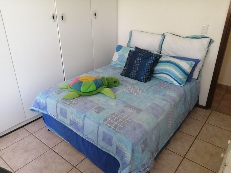 A functional bedroom featuring built-in cupboards and neutral tiled flooring, providing a clean and practical space.