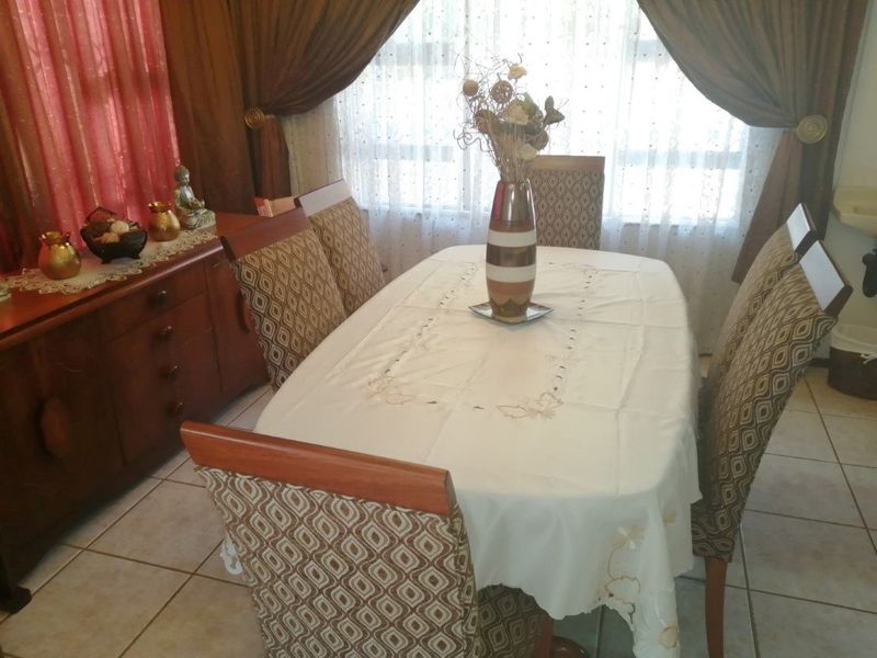 A functional dining room featuring tiled flooring and large windows with curtains, providing a bright and traditional space for family meals.