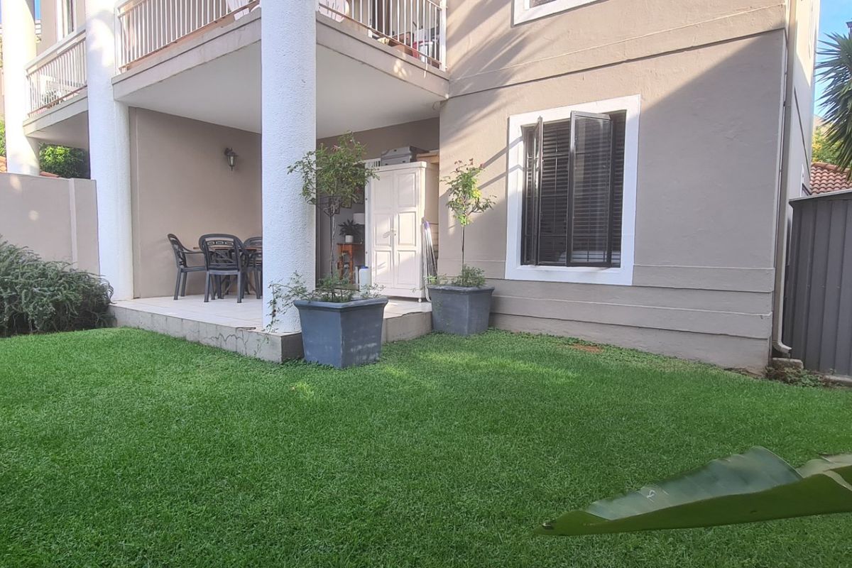 A well-maintained rear garden featuring a covered patio, tiled flooring, and a practical metal storage shed, providing a functional outdoor living space.