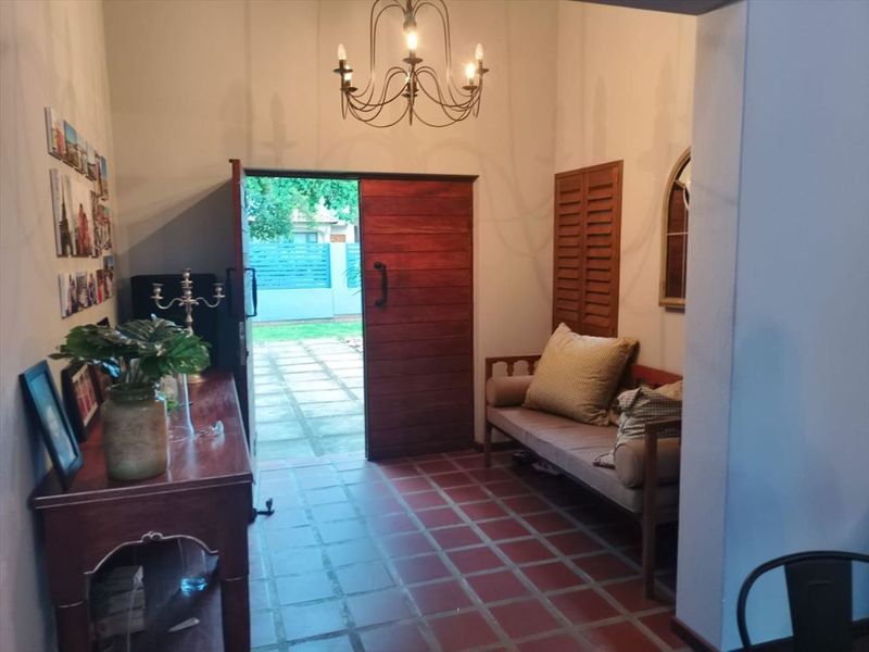 Welcoming entrance hall featuring terracotta tile flooring, a rustic timber door, and a classic wrought iron chandelier.