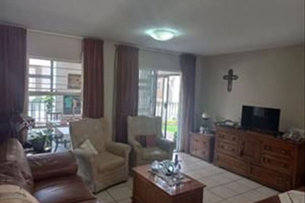 A comfortable living room featuring tiled flooring and sliding glass doors that provide access to the outdoor area.