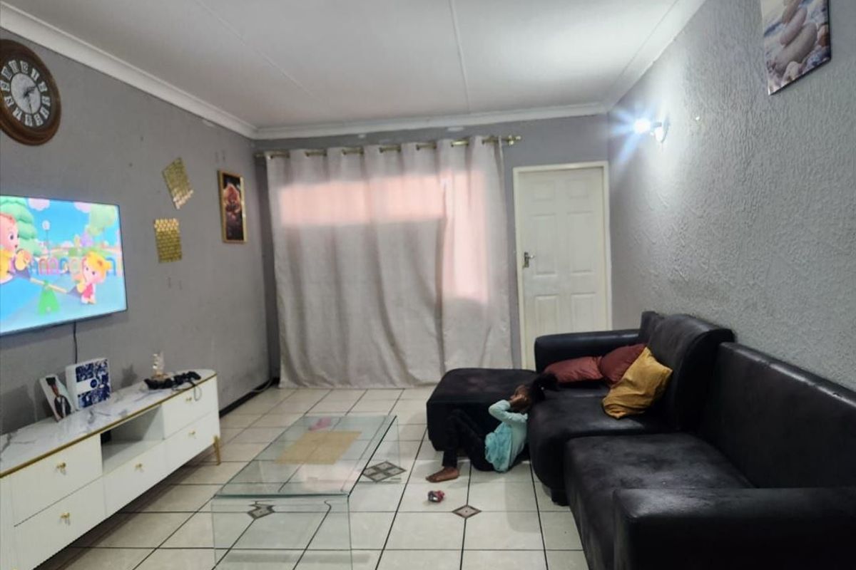 A living room featuring tiled flooring and neutral grey walls, providing a functional space for relaxation and entertainment.