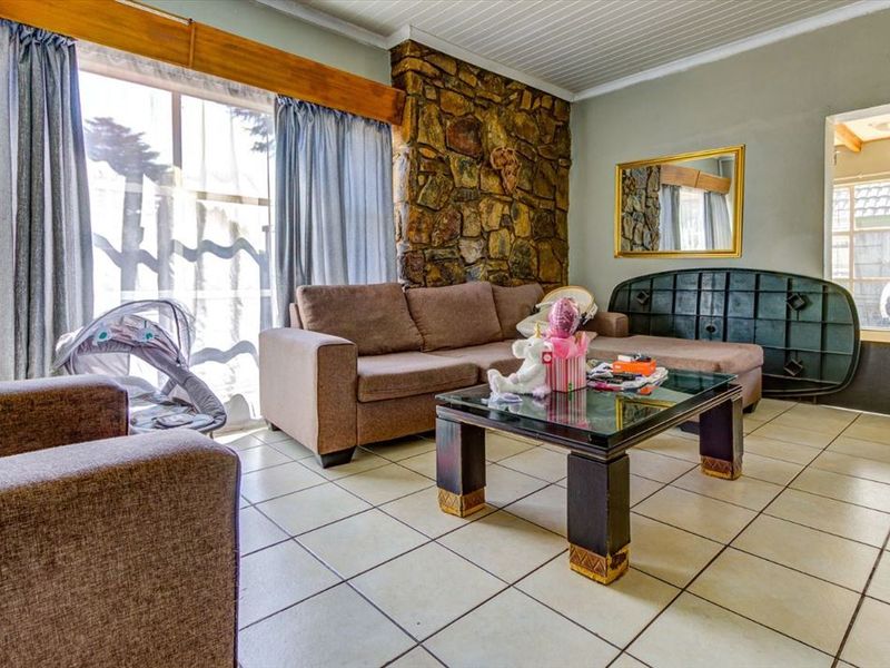 A living room featuring a prominent stone feature wall, ceramic tiled flooring, and a timber-accented window frame.