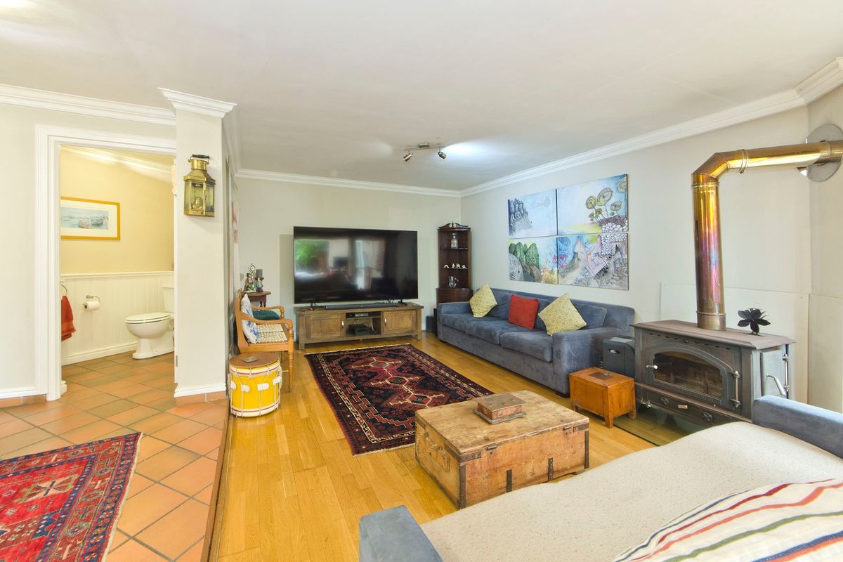 A comfortable living room featuring hardwood floors, a wood-burning stove, and direct access to an adjacent bathroom with tiled flooring.