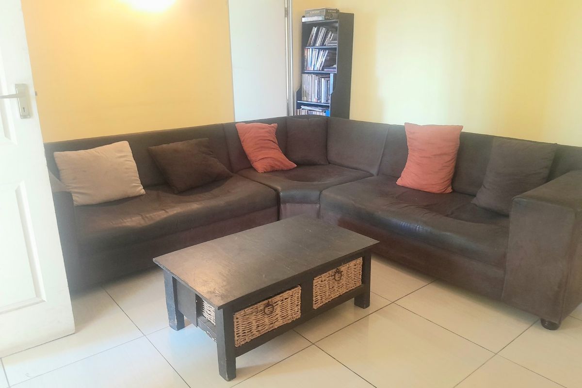 A living room area featuring neutral tiled flooring and yellow wall finishes.