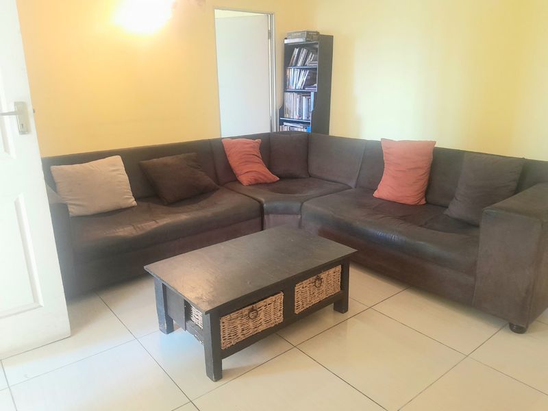 A living room area featuring neutral tiled flooring and yellow wall finishes.