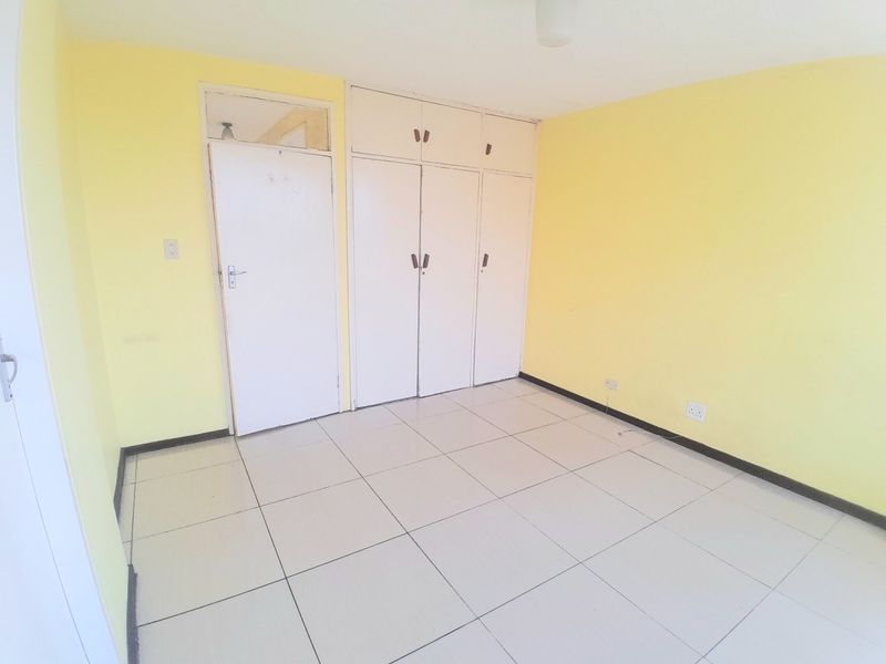 An empty bedroom featuring tiled flooring and built-in storage cupboards with overhead compartments.