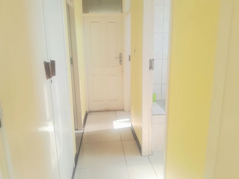 A bright, functional hallway featuring tiled flooring and built-in storage cupboards, providing access to adjacent rooms within the apartment.