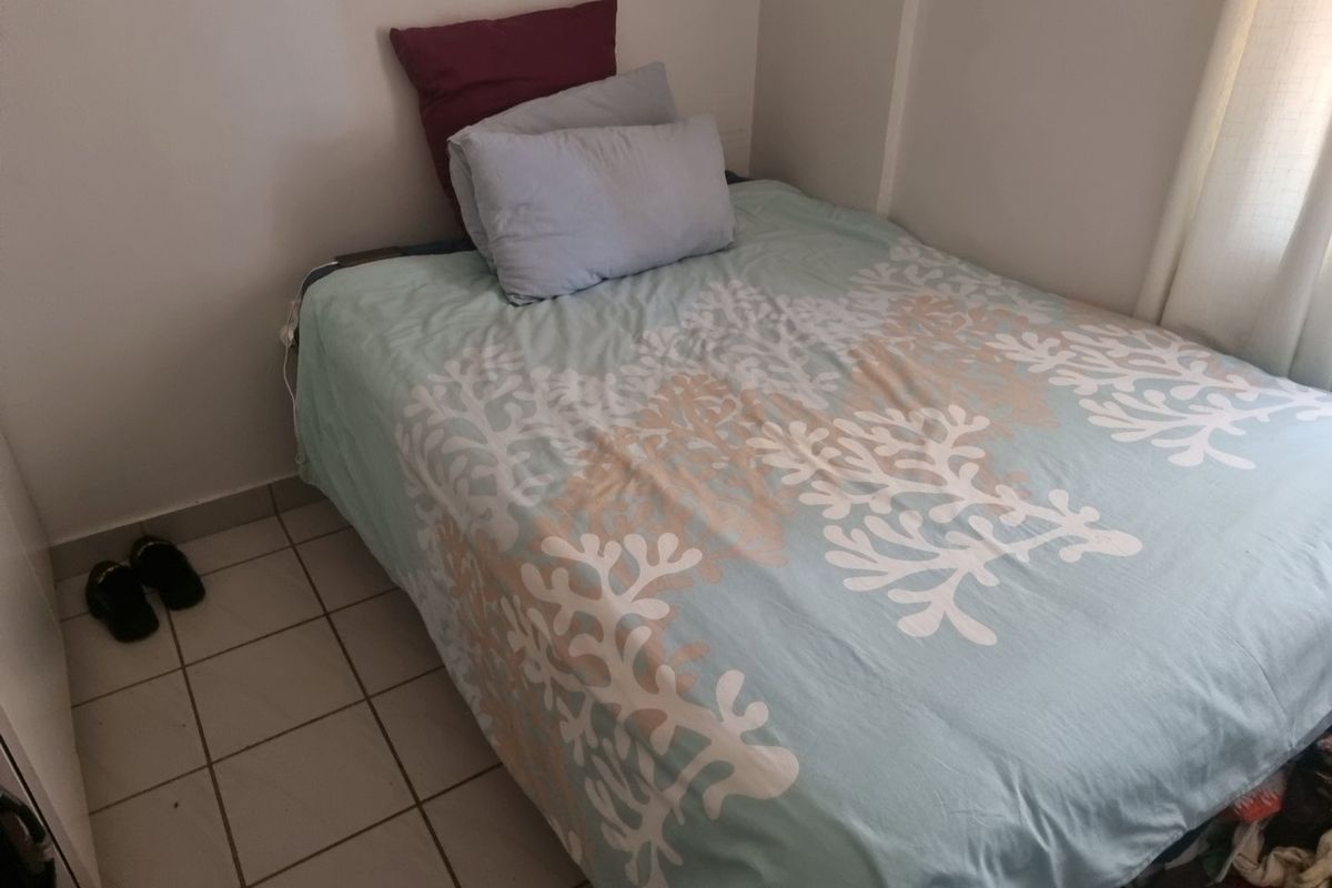 A compact bedroom featuring tiled flooring and neutral wall finishes, providing a functional space for a single bed setup.