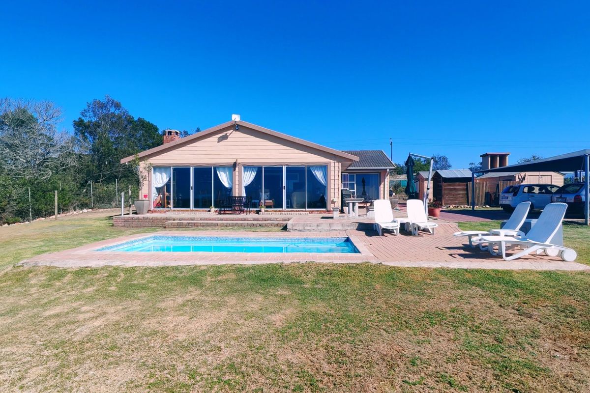 Rear view of the farmhouse featuring a swimming pool, brick paved patio area, and large sliding glass doors leading into the main living space.