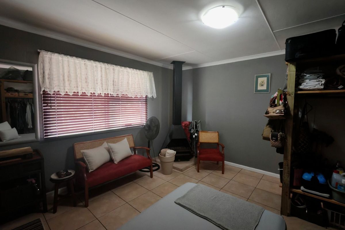 A living room featuring tiled flooring, a freestanding fireplace, and neutral grey walls, providing a functional and cozy space.