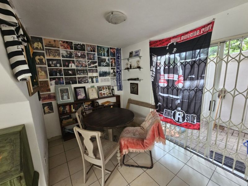 A living area featuring tiled flooring and a sliding glass door with a security gate, providing access to the exterior.