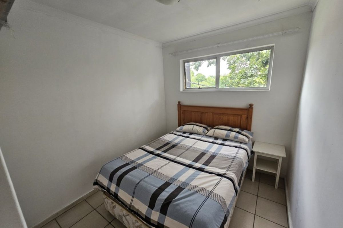 A compact bedroom featuring tiled flooring and a sliding window, offering a functional space ready for cosmetic updates.