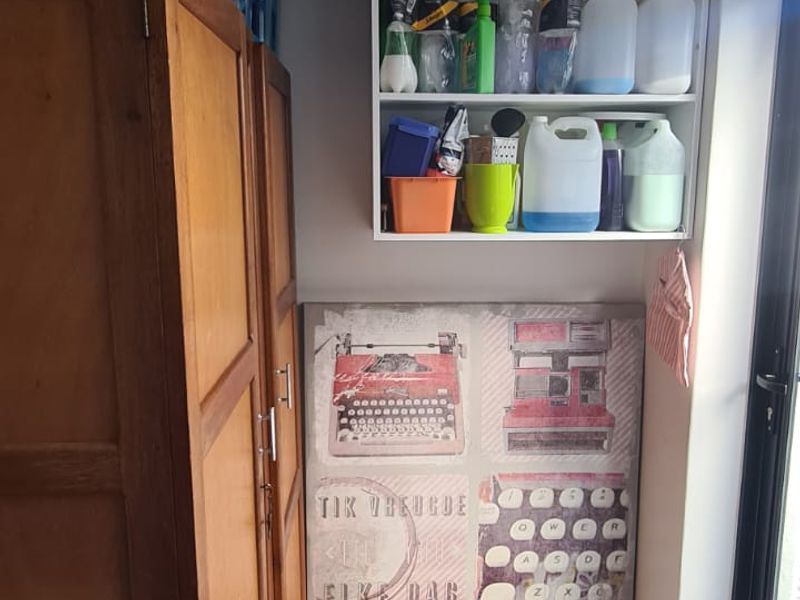 A functional utility space featuring built-in cabinetry, wall-mounted storage shelving, and durable tiled flooring, providing practical storage solutions.