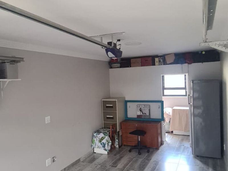 A functional garage space featuring modern wood-look tiled flooring and an automated garage door motor.