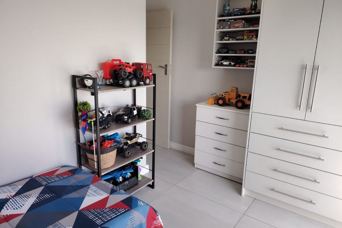 A well-maintained bedroom featuring neutral walls, large format floor tiles, and extensive built-in cabinetry with integrated shelving and drawer storage.