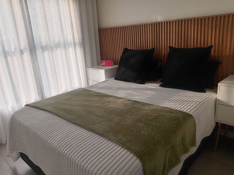 A well-maintained bedroom featuring a modern timber slat feature wall and floor-to-ceiling sheer curtains, creating a warm and inviting atmosphere.