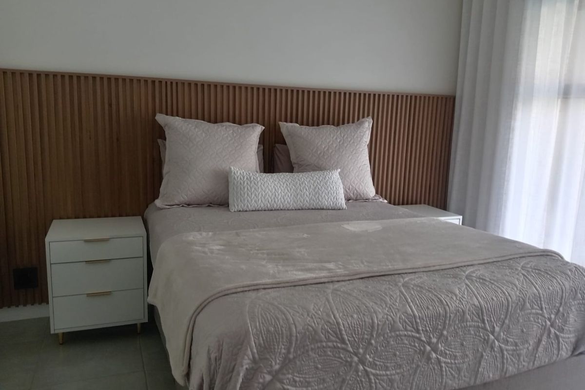 A well-maintained bedroom featuring a modern timber slat feature wall and floor-to-ceiling curtains, creating a warm and inviting atmosphere.