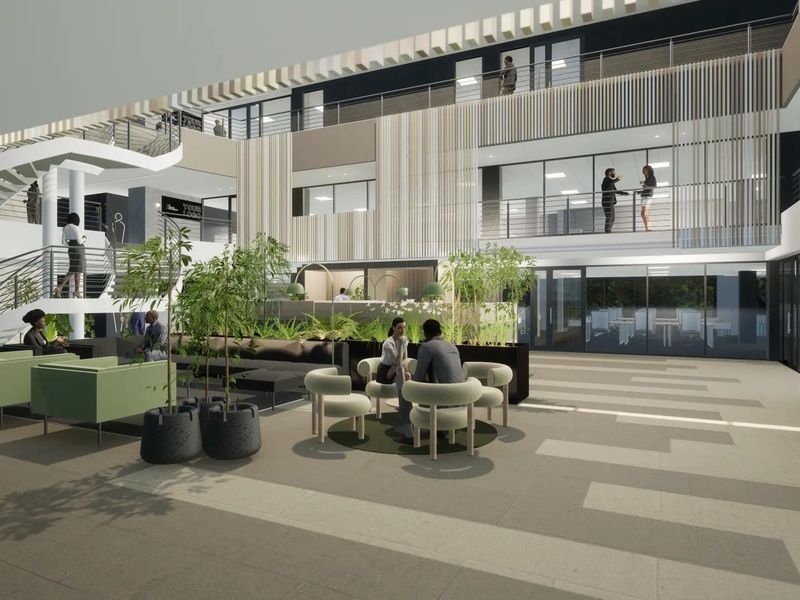 A modern commercial courtyard featuring a multi-level atrium, architectural staircase, and open-air design with integrated timber screening and glass balustrades.